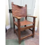 A set of eight rustic oak dining chairs with simple hide panelled seats and backs with brass stud