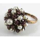 A vintage yellow metal dress 'Princess' ring of unusual design set with garnets and cultured pearls,