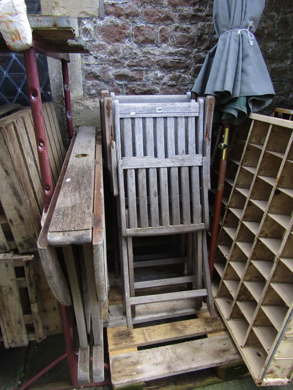 A weathered teakwood folding garden table together with four matching folding teakwood garden chairs