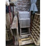 A weathered teakwood folding garden table together with four matching folding teakwood garden chairs