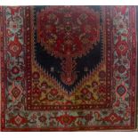 A Persian style wool carpet with red ground medallion upon a blue field and further geometric detail