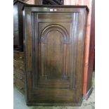 An 18th century oak hanging corner cupboard enclosed by an arched panelled door