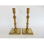 A pair of 18th century cast brass turned candlesticks on stepped square bases, 26 cm high approx.