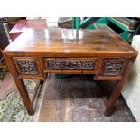An early 19th century Chinese hardwood side table fitted with three frieze drawers, each with carved