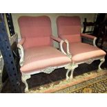 A pair of open armchairs with upholstered seats and backs and with carved and painted framework