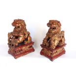 A pair of carved wooden gilt wood and gesso Dogs of Fo with spherical balls in their open mouths