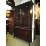 An Edwardian oak bookcase, the lower section enclosed by a pair of quarter panelled doors, the upper