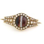 A 15ct gold Victorian brooch set with cabochon banded agate to centre, and pearl encrusted mount,