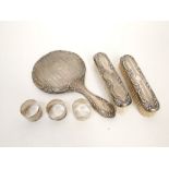 Three silver napkin rings, a silver backed dressing mirror and two silver backed brushes