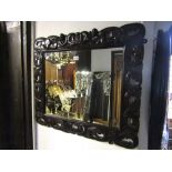 A Carolean style wall mirror in a carved and pierced oak frame with cherub, crown and other