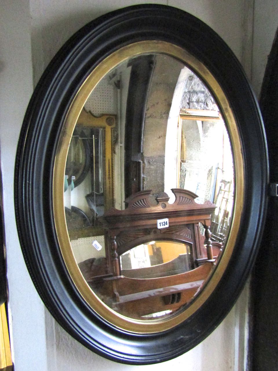 A pair of 19th century style oval wall mirrors in moulded frames and with gilded slips enclosing