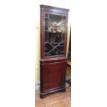 A 19th century mahogany freestanding corner cupboard, the lower section enclosed by a panelled door,