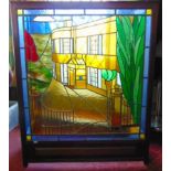 A triptych folding screen centrally fitted with a leaded glass panel with a manor house scene.