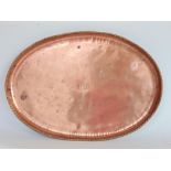 An Arts & Crafts oval copper tray with barley twist borders, inscribed verso H Barnes, The Forge,