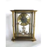 A German cast brass quartz torsion clock, within a four pillared case, 25cm high