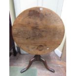 A Georgian country made snap top table in oak and elm raised on a vase shaped pillar and tripod, the