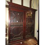 A Georgian mahogany bookcase enclosed by astragal glazed panelled doors beneath blind fret and