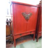 A 19th century Chinese crimson lacquered cabinet enclosed by two simple doors over two frieze