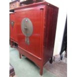 A 19th century Chinese red lacquer cabinet enclosed by two simple drawers with applied engraved