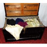 A Wooden trunk with upholstered lid containing a quantity of vintage clothing including a 1950s