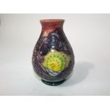 An unusual Moorcroft pottery vase with stylised tree and sunrise detail against a border of fruit