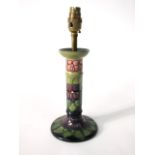 A Moorcroft lamp base with stylised purple violet floral and leaf decoration on a green and black