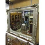 A large overmantle mirror in a moulded silvered lustred frame, the mirror plate with bevelled edge