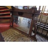 An Arts & Crafts oak framed overmantle mirror with shaped frame and bevelled edge mirror plate