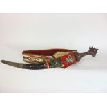 A large eastern ceremonial janbiya with white metal beaded hilt and lacquered studded sheath upon