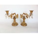 A pair of gilt metal table sconces with scrolled branches mounted by cherubs upon swept circular