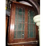 A Regency mahogany hanging corner cupboard enclosed by a pair of astragal glazed panelled doors with