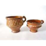 A 19th century earthenware vessel with simple handle and pouring spout with trailed slip border