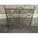 A good quality hand wrought iron work firescreen with scrolled detail and mesh back, 70 cm wide