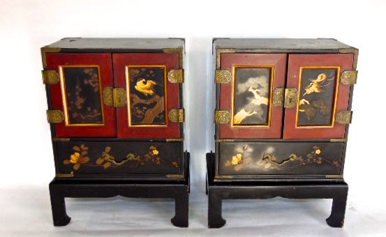 A pair of Japanese lacquered table top cabinets, the panelled doors decorated in gilt with birds