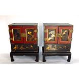 A pair of Japanese lacquered table top cabinets, the panelled doors decorated in gilt with birds