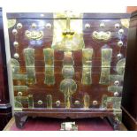 A 19th century Korean elmwood chest heavily overlaid in brass and raised on scrolled supports, brass