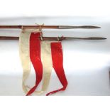 A pair of bamboo pig sticking spears, with triform metal spoked ends each tied with a red and