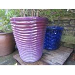 A contemporary purple glazed planter of circular tapered form with ribbed detail, containing a