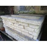 A pair of cast composition stone garden planters of rectangular form with mock stone wall facade