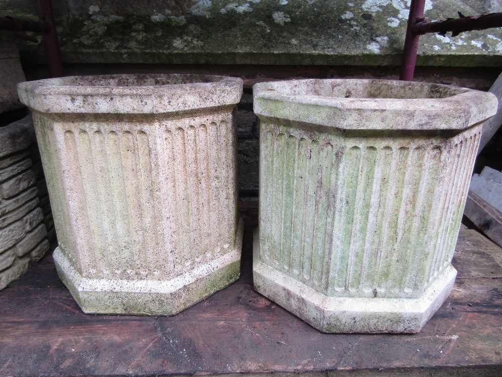 A pair of cast composition stone garden planters of octagonal form with fluted detail