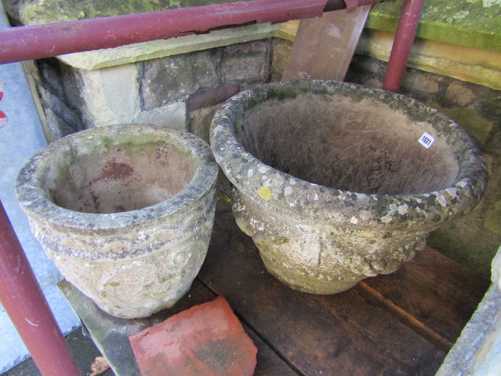 Two weathered cast composition stone garden planters of varying design with decorative relief