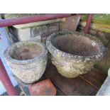 Two weathered cast composition stone garden planters of varying design with decorative relief