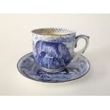 A unusual early 20th century outsized cup and saucer with blue painted decoration, the cup showing a