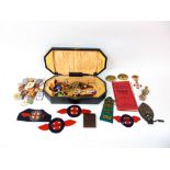 A shaped leather box containing a collection of various badges and patches