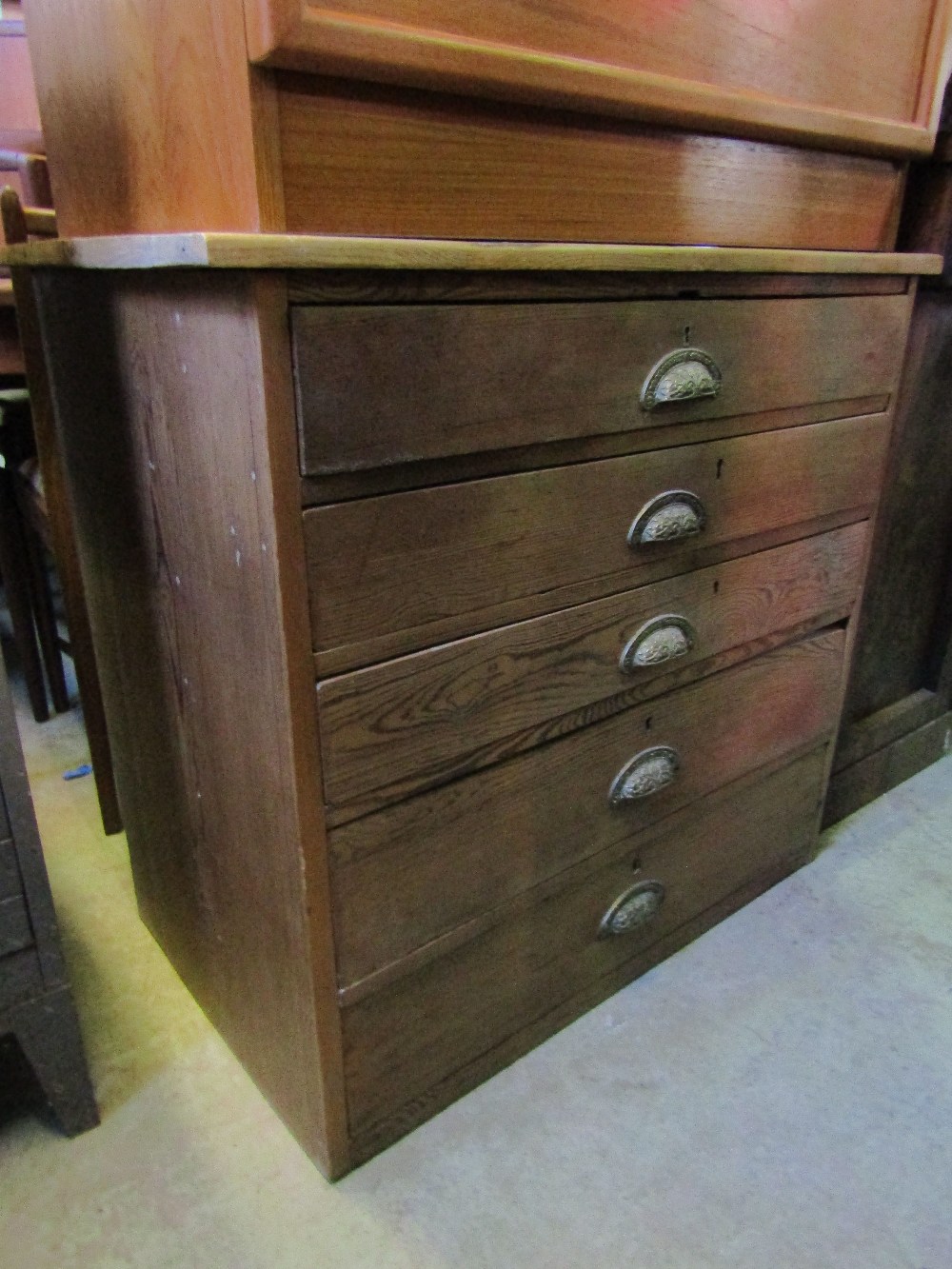 A Victorian pitch pine chest of five long graduated drawers with central cast and foliate pattern