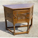 ELM CUPBOARD WITH CANTED SIDES AND CARVED FLORAL DECORATION WITH A PANELLED DOOR ON TURNED