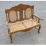 A TWO SEATER BERGERE SEAT WITH CARVED SCROLLING FRUITING VINE DECORATION & PRINCE OF WALES FEATHERS