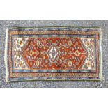 A PERSIAN MADDER & IVORY FIELD RUG WITH A CENTRAL HEXAGONAL MEDALLION AND ALL OVER STYLIZED FLORAL