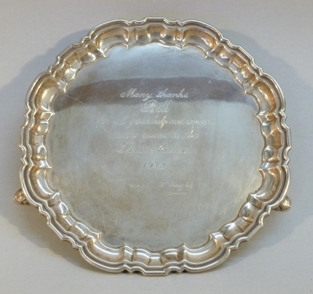 SILVER SHAPED CIRCULAR SALVER WITH INSCRIPTION, DATE 1972, AND A PIECRUST RIM, ON THREE INVOLUTE