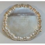 SILVER SHAPED CIRCULAR SALVER WITH INSCRIPTION, DATE 1972, AND A PIECRUST RIM, ON THREE INVOLUTE